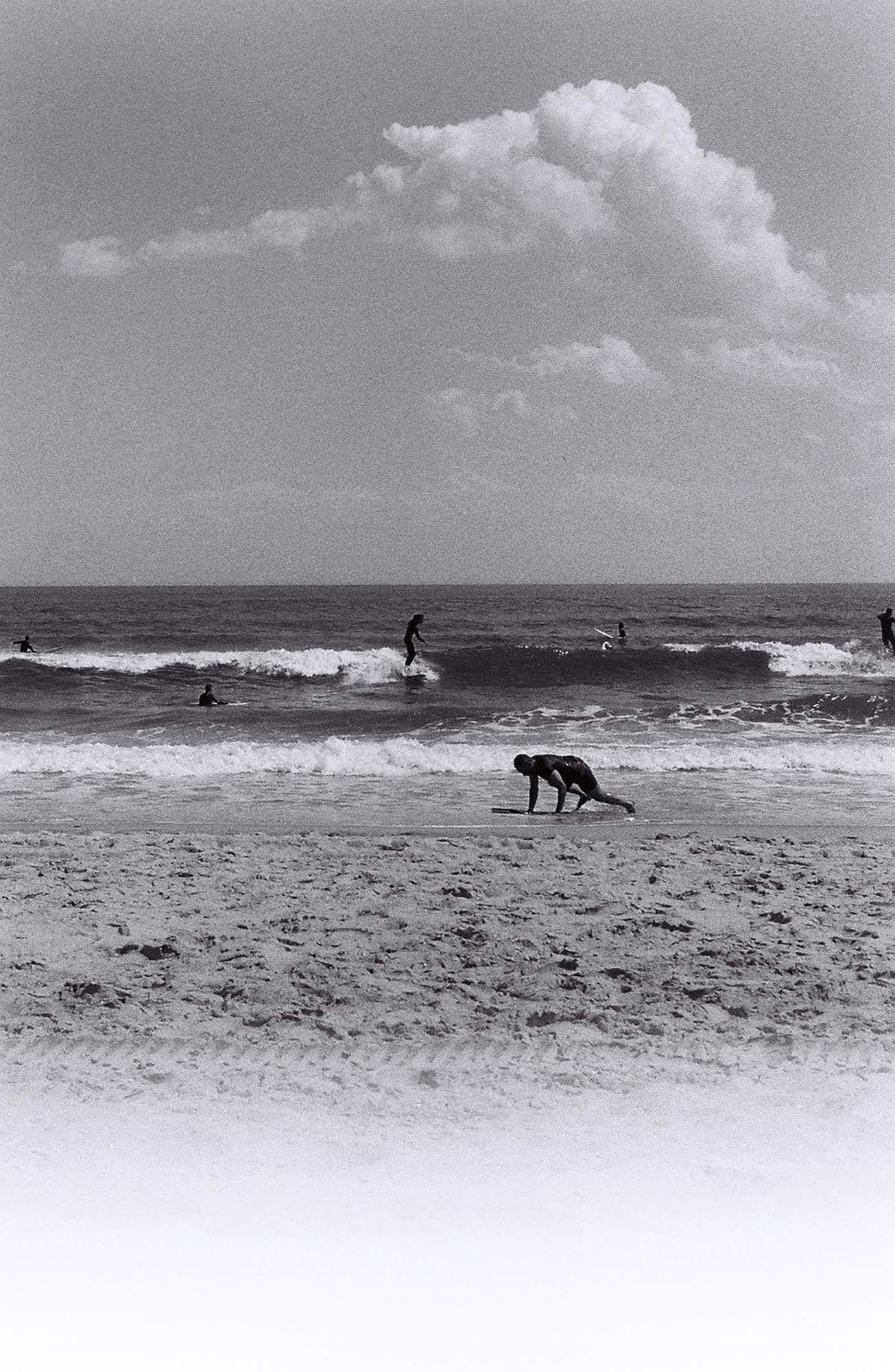 A grainy black and white photograph of people on the beach.